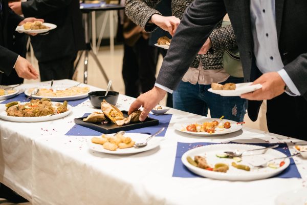 People in suits serve themselves at the buffet and eat delicious food at a business event People in suits serve themselves at the buffet and eat delicious food at a business event. There are snacks and finger food.